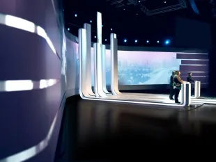 Wahlstudio 2010 in der Wiener Stadthalle mit Balkendiagrammen als Pulten für Kandidat:innen und einer 180-Grad-Projektionswand, vor großem Publikum