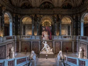 Opulenter Saal mit Marmorwänden und Bögen. Zentrale Skulptur mit Löwen, Rubens-Gemälde darüber, umgeben von Büsten.