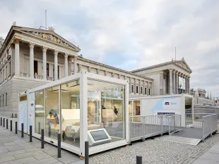 Weiße Container mit Glasfront vor dem Parlament