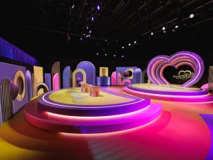 Buntes Studio mit leuchtenden, runden Plattformen, Herzform und farbenfrohen Kulissen.