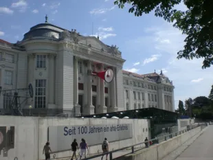 Außenansicht auf technisches Museum, Banner mit "Seit 100 Jahren ein aha-Erlebnis" und übergroßen roten Megaphon über Eingang