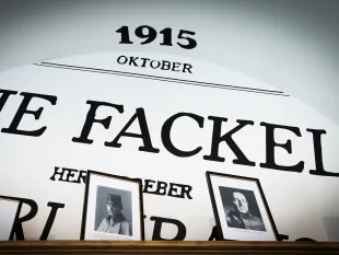 Ausstellungswand mit "1915 Oktober", "Die Fackel" und "Herberd", darunter gerahmte Schwarz-Weiß-Fotos auf Holzregal