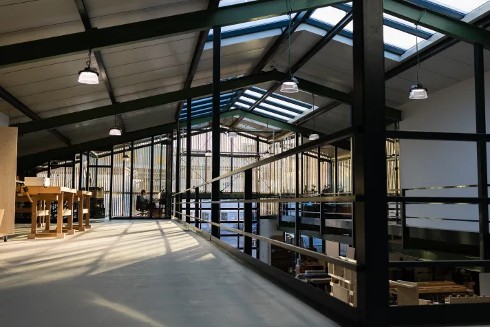 Galerie der Werkstatt mit Glasdach, Holzwerktischen, Balustrade und hängenden Lampen
