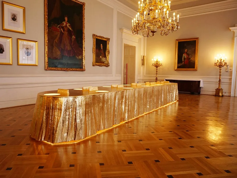 Langer goldener Tisch mit Struktur, große Gemälde historischer Personen an Wand