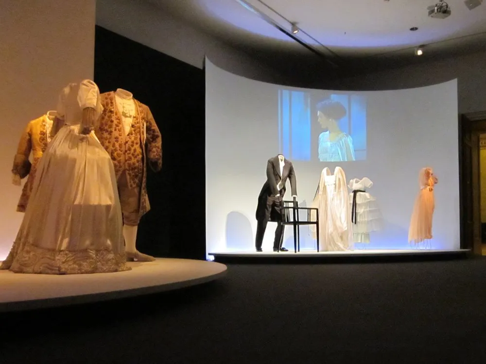 Historische Kleider und Anzug hängen in Ausstellung