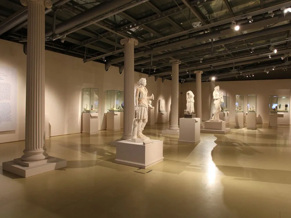 Ausstellungsraum: Antike Marmorskulpturen auf Sockeln, umgeben von Vitrinen und Säulen