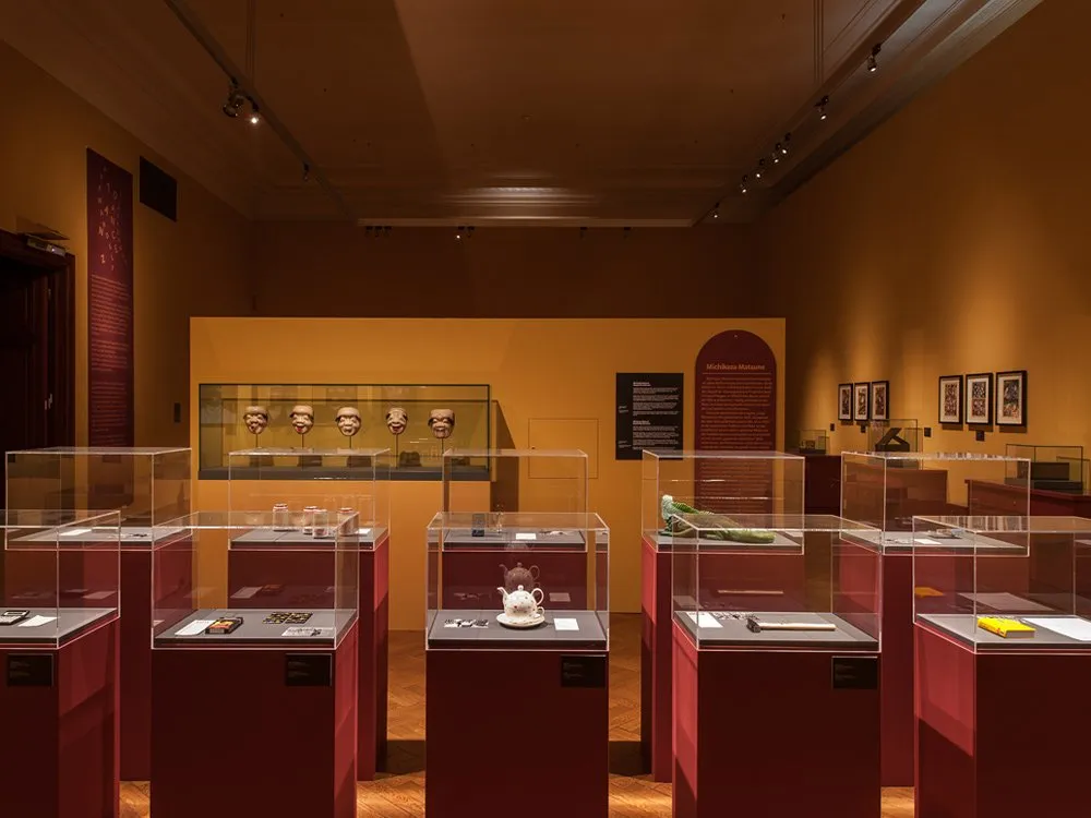 Ausstellungsraum: Vitrinen mit Masken, Teekanne, grünem Objekt und anderen Artefakten