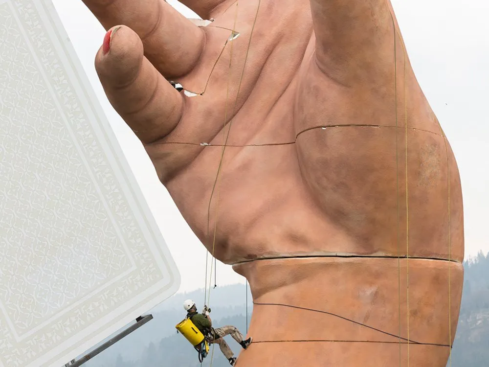 Aufbau der Handteile, Arbeiter in Sicherheitsausrüstung klettert an einer großen Hand