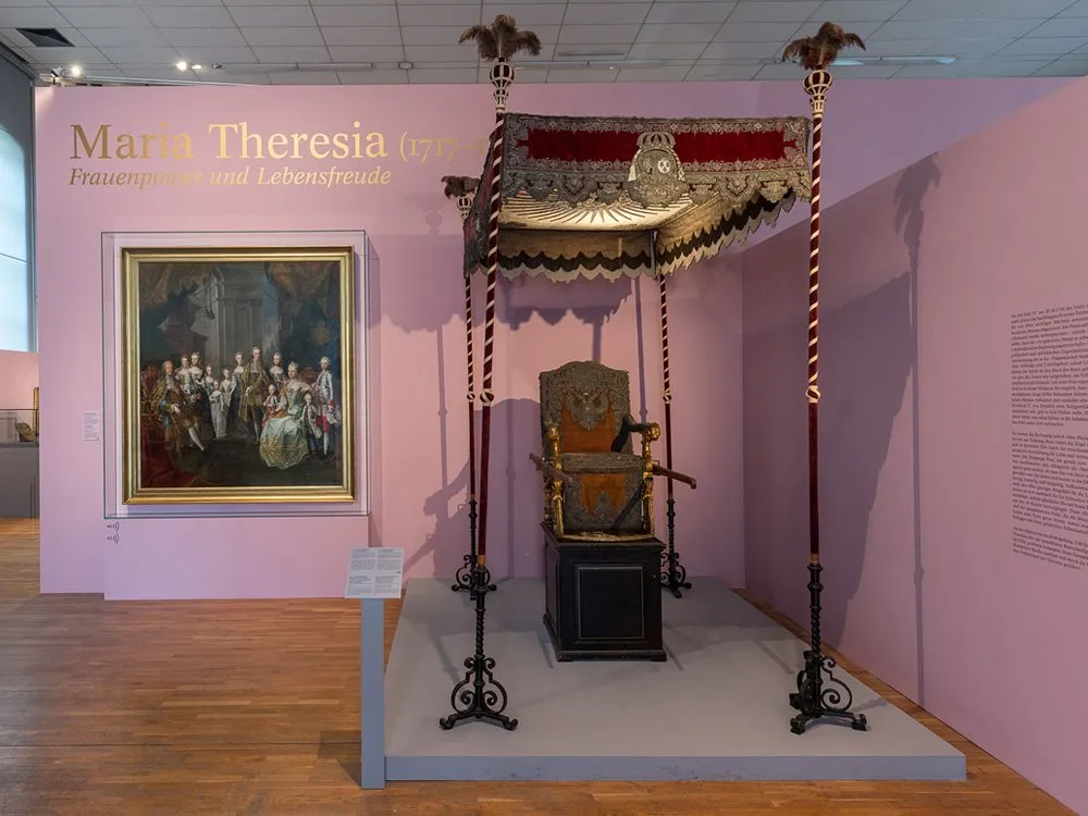 Ausstellungsraum: Thron mit Baldachin, Gemälde der Familie, rosa Wände, Holzboden