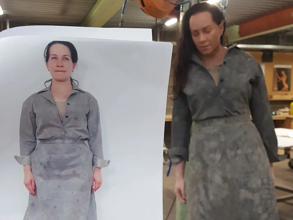 Frau in grauem Kleid neben einem Foto mit identischer Kleidung, Werkstattumgebung