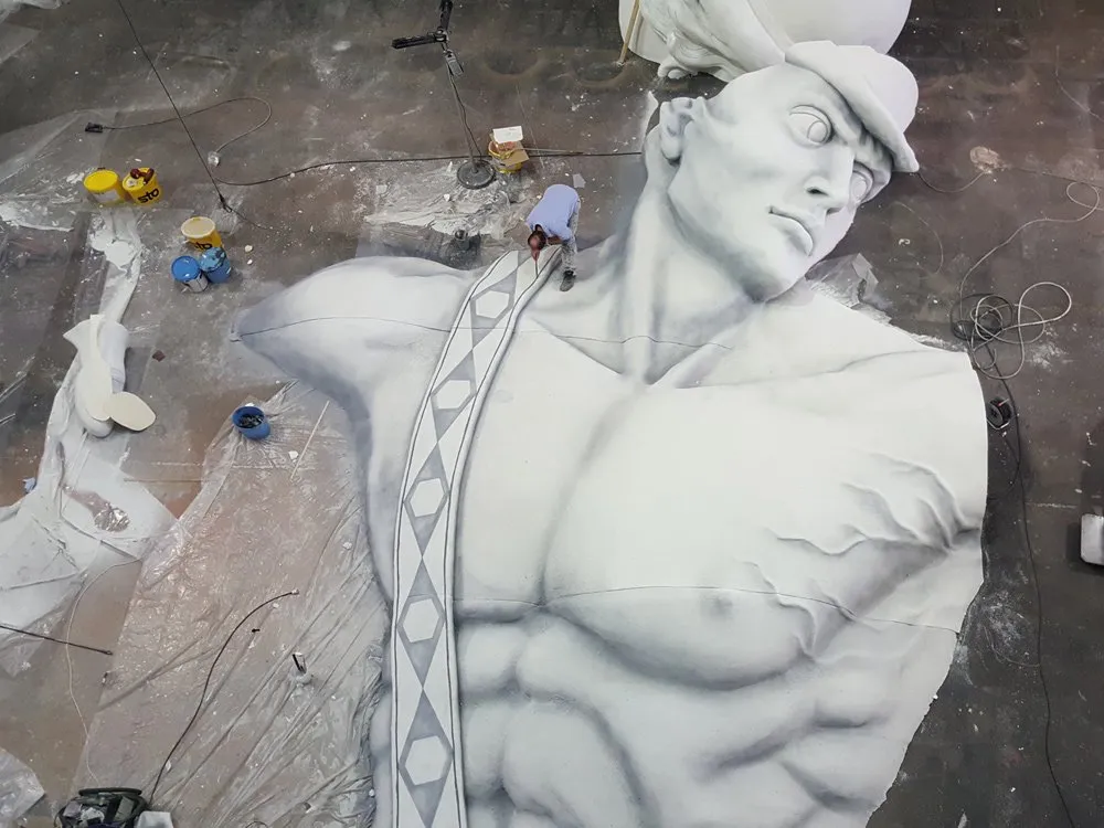 Große Statue eines Mannes in Arbeit, Künstler bei der Bearbeitung, Farbeimer und Werkzeuge