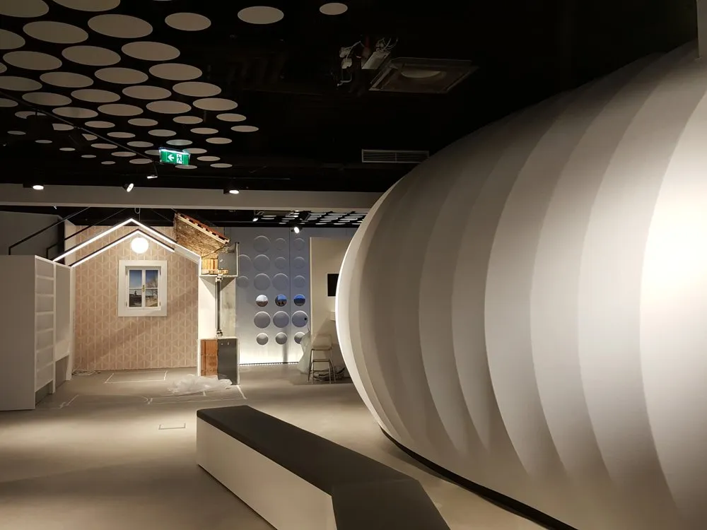 Ausstellungsraum: gewölbte, weiße Struktur, ein Modellhaus mit Fenster