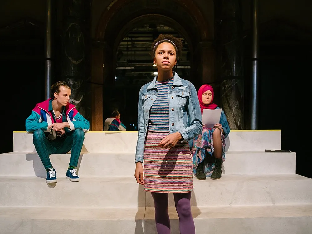 Drei Schauspieler auf weißen Treppen, zwei sitzend eine stehend