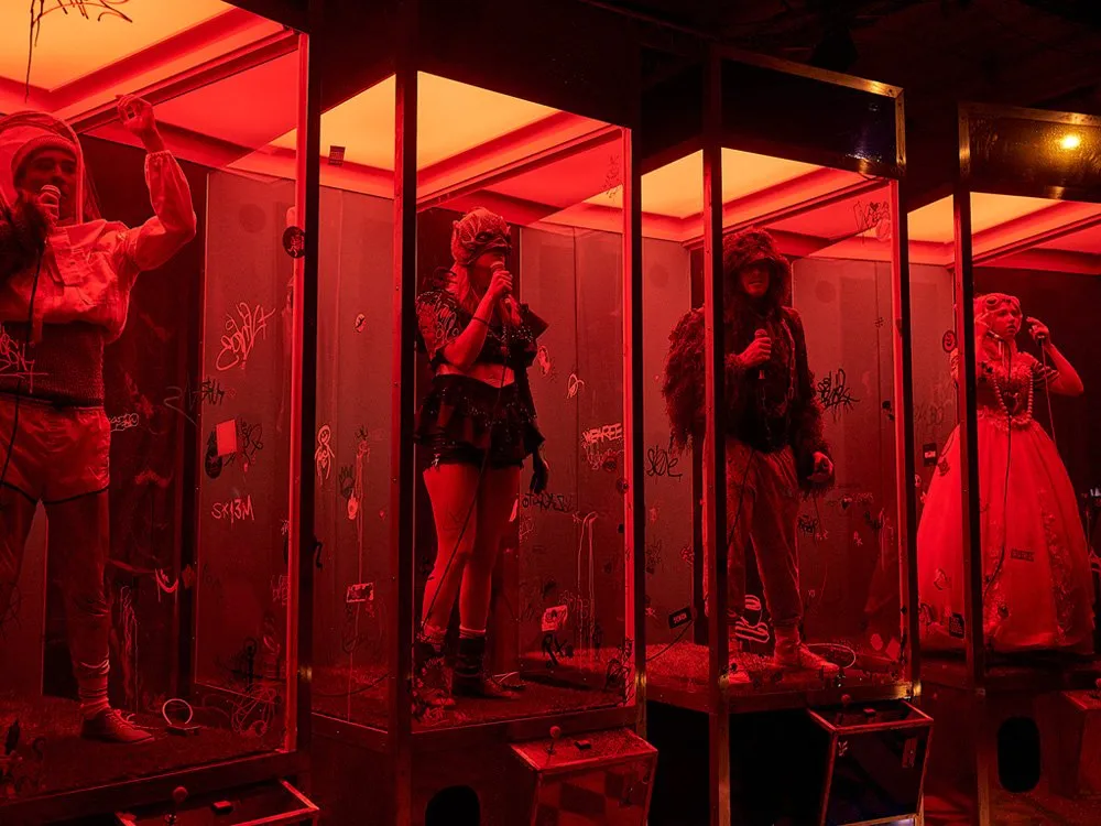 Vier Glasvitrinen mit Personen, rot beleuchtet