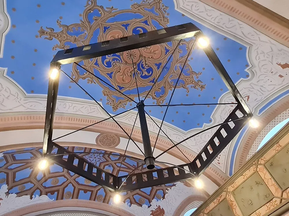 bemalte Decke mit blauem Himmel und ornamentaler Dekoration und schwarzem Kronleuchter