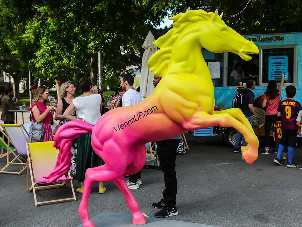 Pferdeskulptur umgeben von Menschen, Liegestühlen und einem Foodtruck.