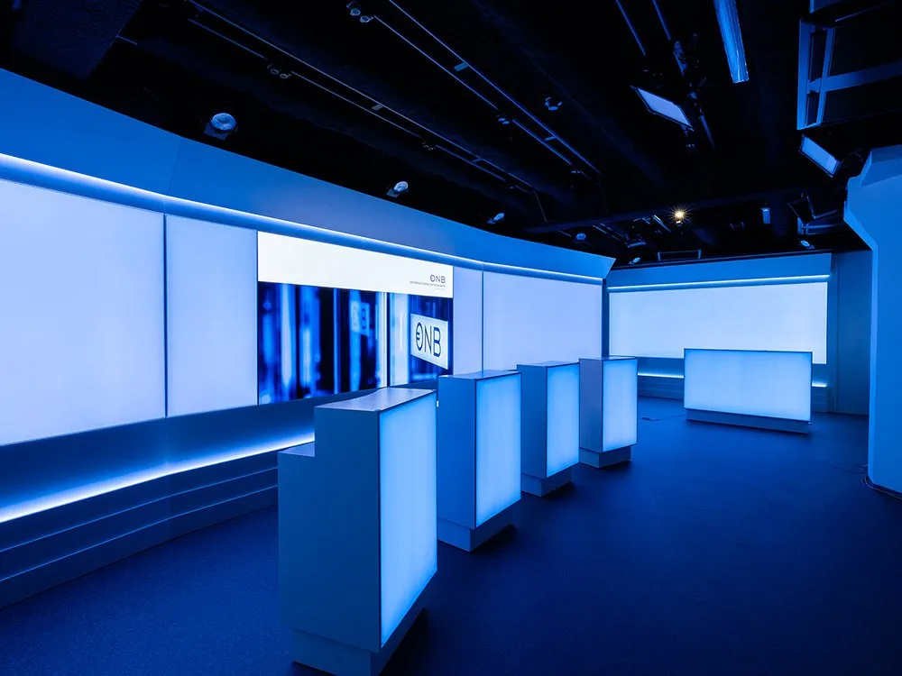 Studio mit vier weißen Pulten, aus seitlicher Perspektive mit blauer Beleuchtung.