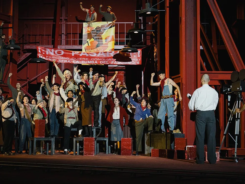 Szene: Gruppe von Darstellern in historischem Gewand, die Banner mit antifaschistischen Slogans schwenken