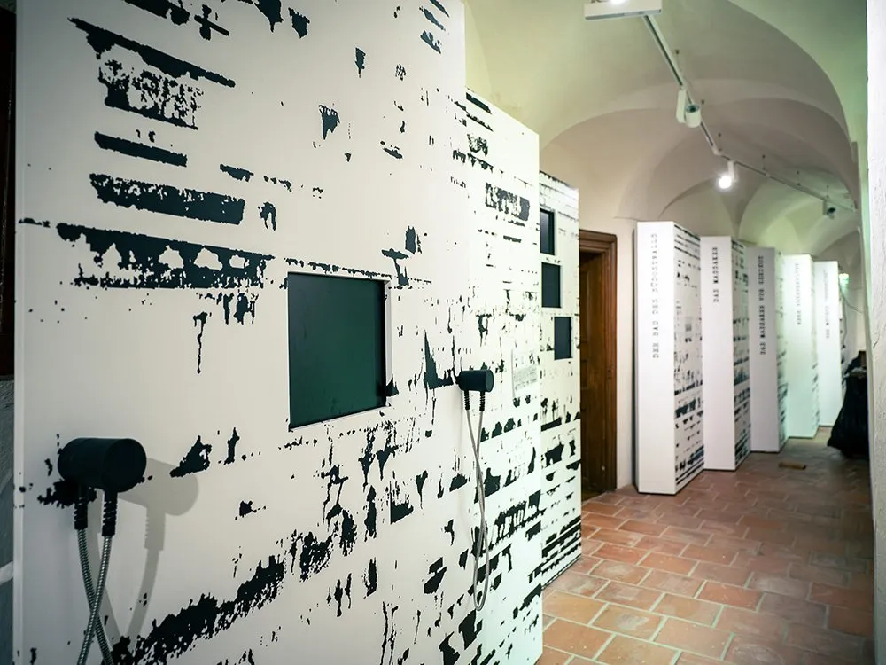 Ausstellungsraum mit gewölbter Decke, beleuchteten Panels mit abstrakten Mustern und einer Reihe von Infotafeln entlang der Wand.