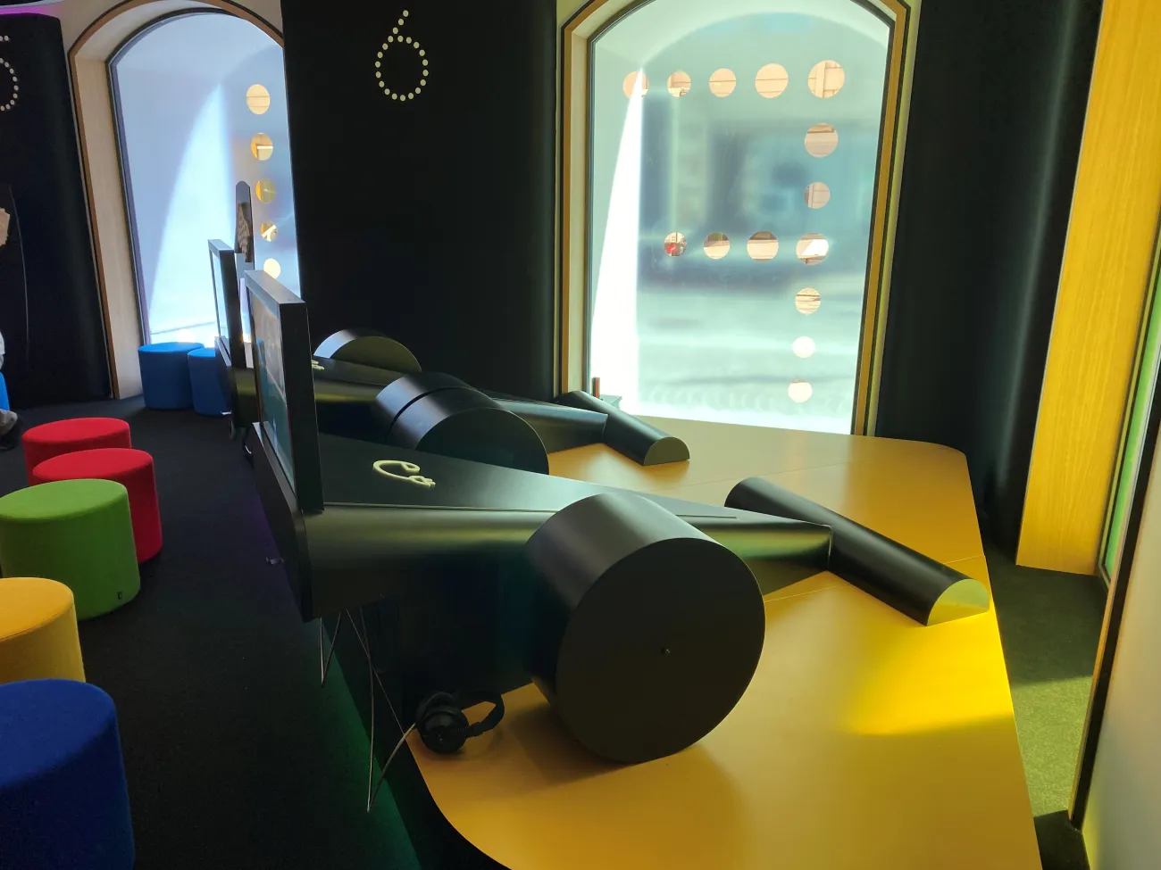Raum mit Interaktivstation, Bildschirme an Rennautos 