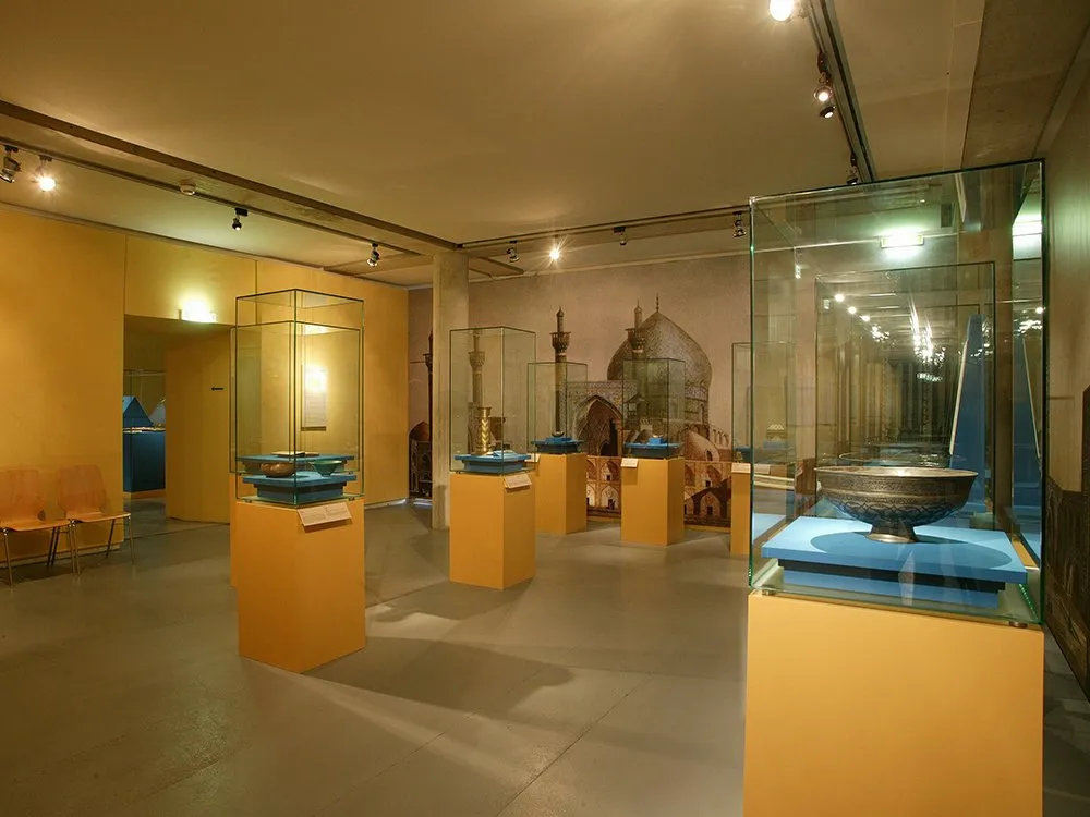 Glasvitrinen auf gelben Sockeln mit antikem Geschirr