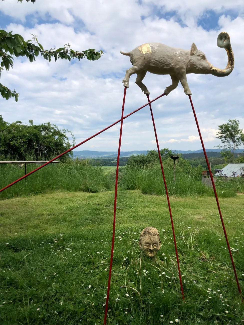 Schwein auf langen roten Stelzen mit Elefantenrüssel