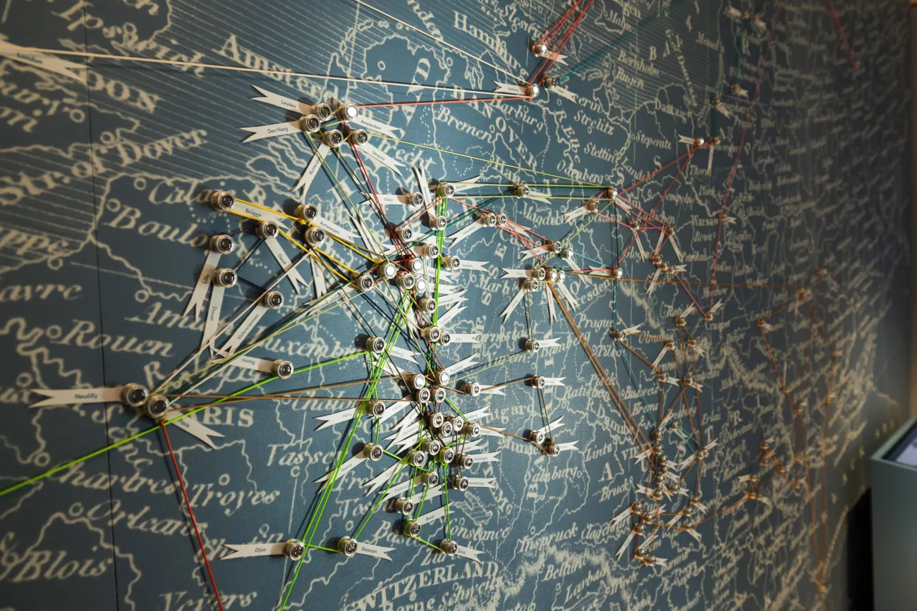 Detailansicht: Weltkarte mit Pins an verschiedenen Städten in Europa, verbunden mit Schnüren