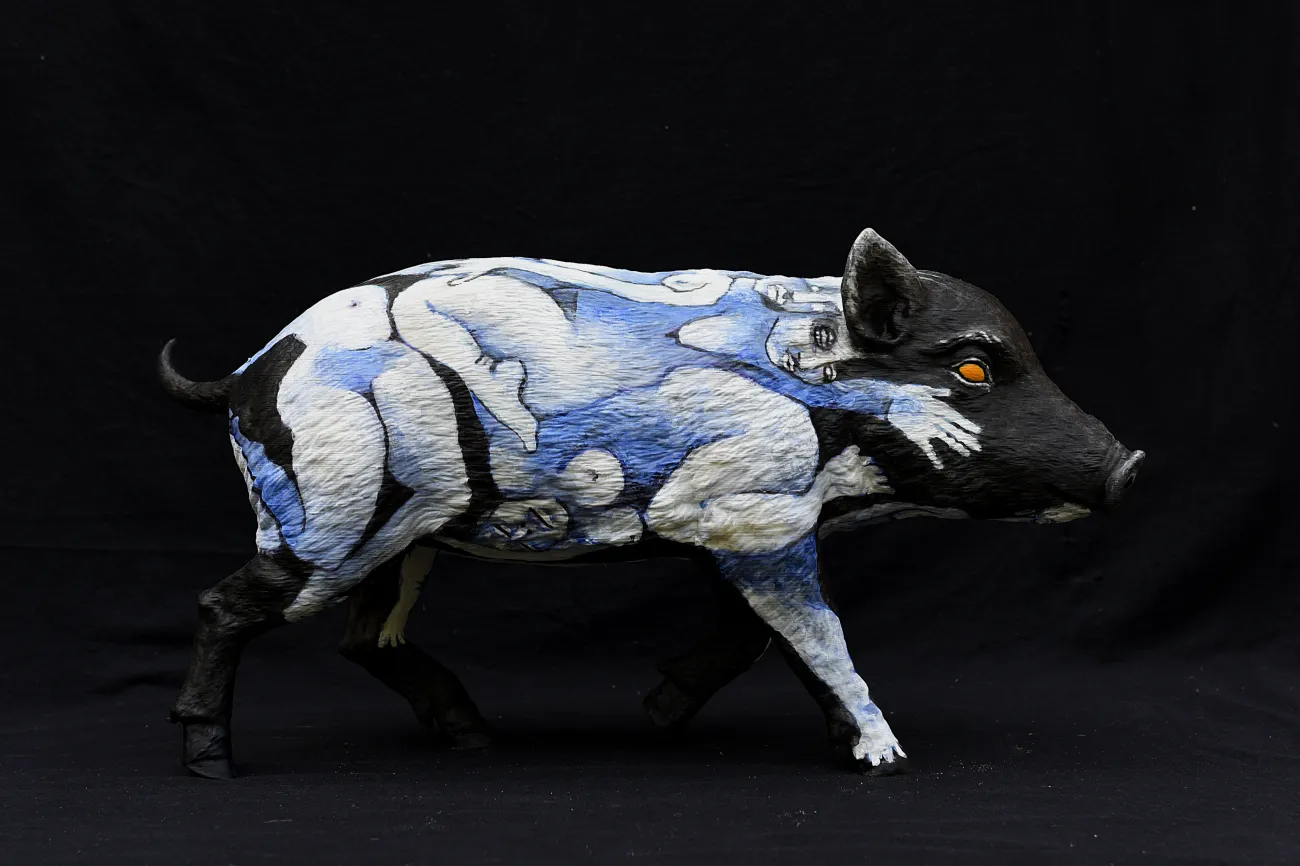 Schwein bemalt mit weißen und blauen Mustern und orangem Auge