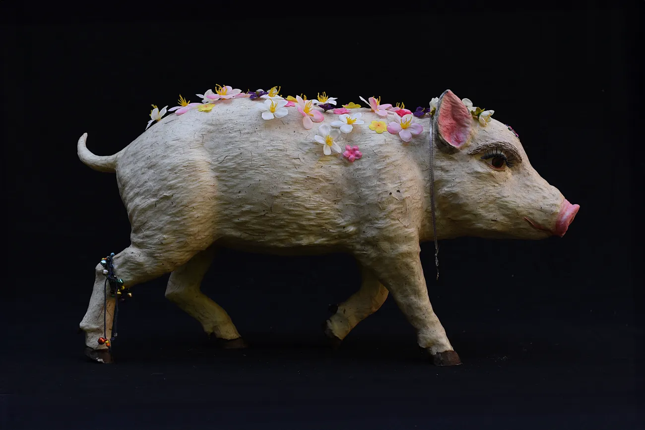 Rosa bemaltes Schwein mit falschen Wimpern und einigen Blumen am Rücken