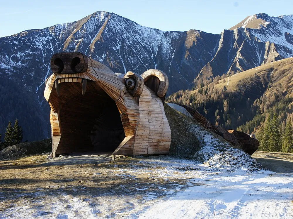 Bärenkopf mit offenem Maul vor Berglandschaft