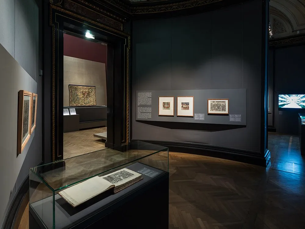 Vitrine mit offenem Buch, kleine Bilder an den Wänden