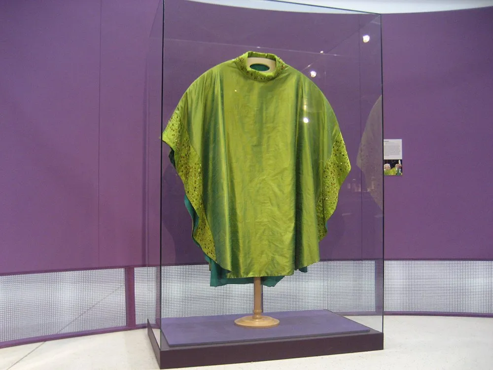 Glasvitrine mit grüne Stola vor einer lila Wand