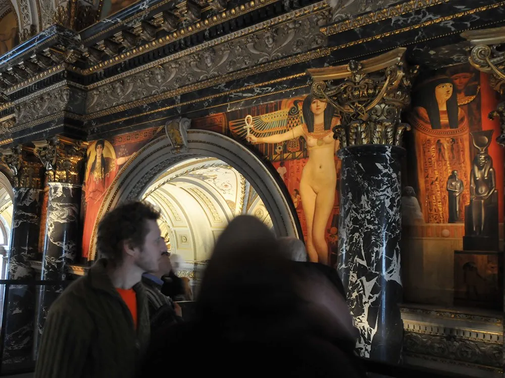 Wand mit ägyptischen Figuren und schwaren Marmorsäulen mit Verzierungen