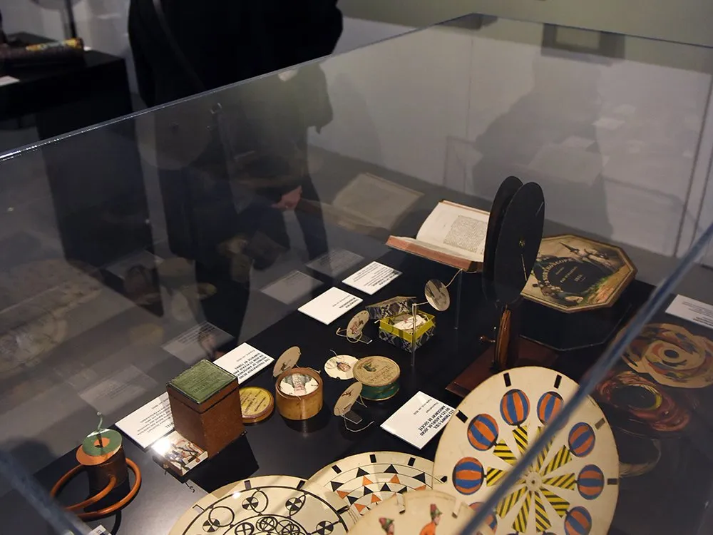 Ausstellung mit Besuchern, die eine Sammlung antiker Schriftrollen und Kalligraphien in Glasvitrinen betrachten