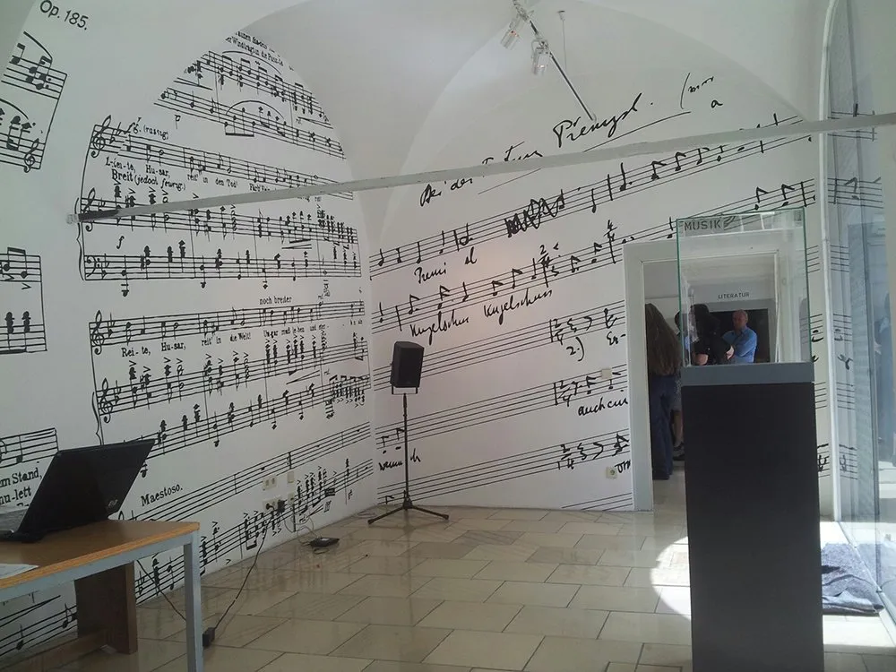 Raum mit Wänden, bedeckt mit Notenblättern, handschriftlichen Notizen und Texten