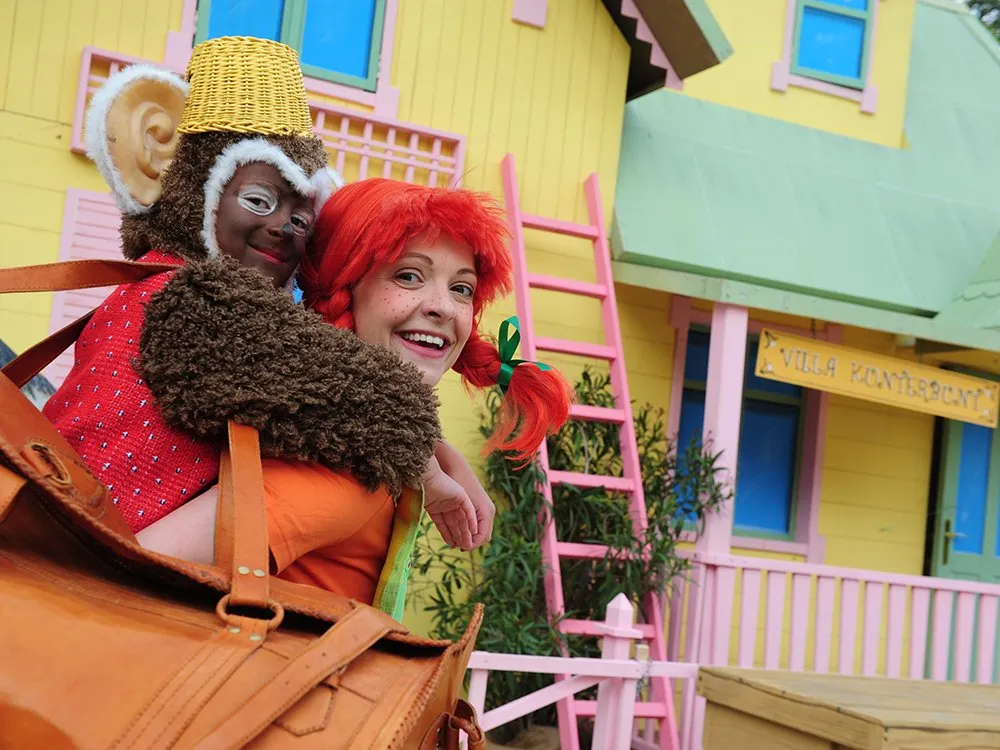 Nahaufnahme: Pippi mit Herr Nilson (Kind in Affenkostüm) am Rücken lächelt in die Kamera