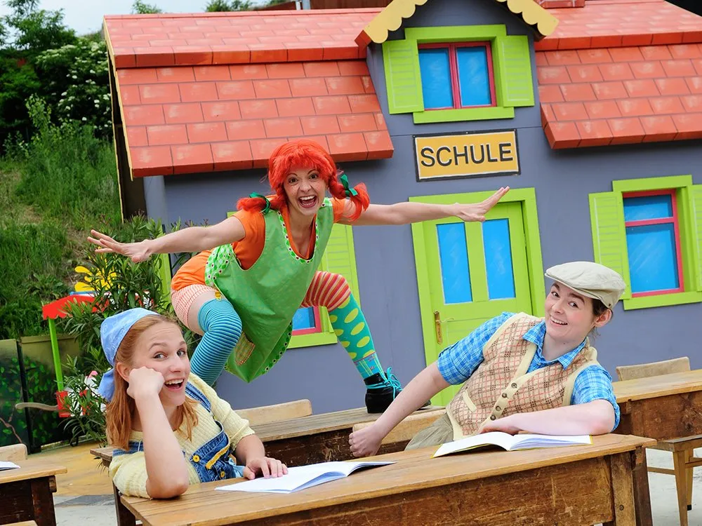 Tommy und Annika auf Schulbänken, Pippi auf Tischen in frecher Pose