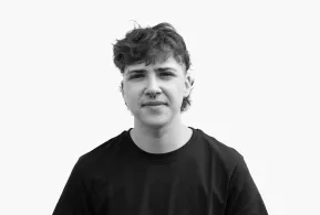 Halbportrait in schwarz-weiß: Junger Mann mit dunklen Haaren, Piercing an Augenbraue und Nase