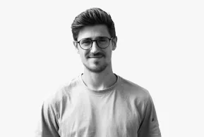 Halbportrait in schwarz-weiß: Junger Mann mit dunklen Haaren, Bart und Brille