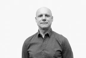 Halbporträt in schwarz-weiß: Mann mit Glatze, trägt bedrucktes Hemd