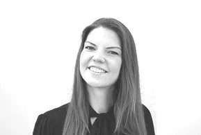 Halbporträt in schwarz-weiß: lächelnde Frau mit langen, glatten Haaren, trägt dunkles Oberteil mit Schleife