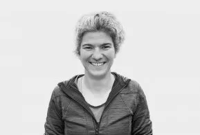 Halbporträt in schwarz-weiß: Frau mit kurzen, lockigen Haaren, trägt dunkle Jacke