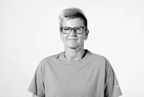 Halbporträt in schwarz-weiß: Frau mit kurzen Haaren und Brille, trägt helles Oberteil