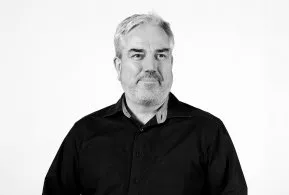 Halbporträt: Mann mit grauem Haar und Bart in dunklem Hemd